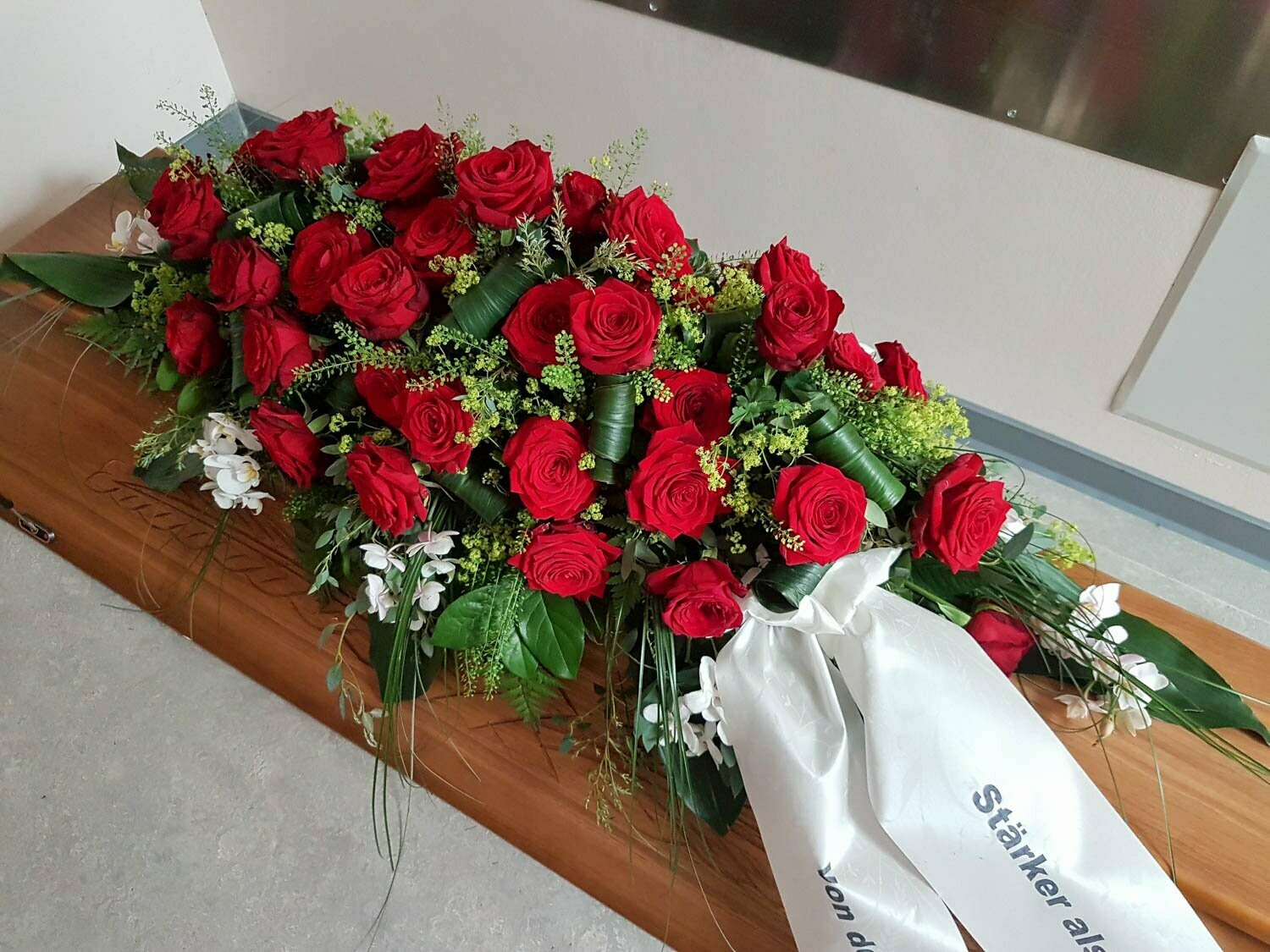 Sargschmuck - längliches Bukett mit roten Rosen und weißen Orchideen